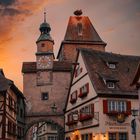 Hotel Markusturm an mittelalterlicher Stadtmauer, Uhrturm, Fachwerkhäuser, blumengeschmückte Fenster, dramatischer Abendhimmel.