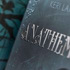 Der Text "A NATHE" ist in geschwungener silberner Schrift auf einem dunkelblauen Hintergrund sichtbar.