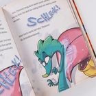 Text: "SCHLECK! Aber doch nicht bei mir, Flammi! Ih, Schlabberalarm!"  
Illustration: Ein grüner, cartoonartiger Drache mit offenem Mund und einer großen rosa Zunge.