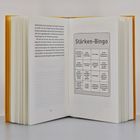 Text oben: "Stärken-Bingo". Unten Felder mit Aussagen wie "Ich war mutig". Buch mit gelbem Einband, viele Seiten.
