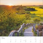 "Mai" oben links mit Kalendertagen darunter. Eine Treppe führt durch grüne Wiesen, Sonnenuntergang im Hintergrund.