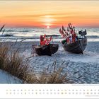 Mai-Kalenderblatt mit Foto von Fischerbooten am Strand bei Sonnenuntergang. Im Hintergrund Wellen und grasbewachsener Sand.
