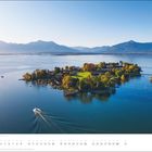 Text: "Mai." Kalenderansicht. Insel im blauen See, umgeben von Bergen. Ein Boot zieht eine Spur durchs Wasser.