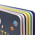 „NO, IS BETT“ auf einem mehrfarbigen, gestapelten Kinderbuch mit einem Planeten und Stern.