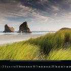 Mai 2023; Küste mit grünen Gräsern im Vordergrund, Felsen im Meer, bewölkter Himmel, Kalender.