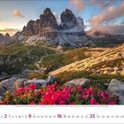 Mai 2023 Kalenderblatt mit Berglandschaft, felsigen Gipfeln, bewölktem Himmel und rosa Blüten im Vordergrund.
