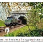 Eine alte Lokomotive fährt aus einem Tunnel. Unten sind die Monats- und Tageszahlen für Mai in Rot und Schwarz.