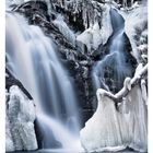 Großes Datum zeigt 04 JANUAR. Vereister Wasserfall mit eisbedeckten Felsen und fließendem Wasser im Winter.