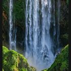 "5" oben, Monatskalender für Mai. Majestätischer Wasserfall, umgeben von üppigem Grün und felsiger Landschaft.