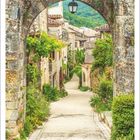 5 | 2027. Ein idyllischer Weg durch ein historisches, steingemauertes Dorf mit üppigen Pflanzen und einem hängenden Laternenbogen.