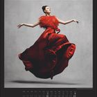 Mai-Kalenderseite. Frau in rotem, fließendem Kleid springt anmutig vor grauem Hintergrund.