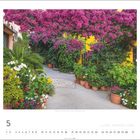 Text: "Capoliveri, Elba, Toskana, Italien". Eine blühende Gartenszene mit bunten Blumen und Töpfen vor einer gelben Wand.