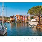 „Port Grimaud an der französischen Riviera, Frankreich. Juni, Woche 23.“ Yachten im Wasser vor bunten Häusern.