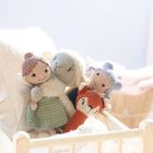 Vier gehäkelte Stofftiere auf einem gemütlichen weißen Kissen in einem hellen Raum.