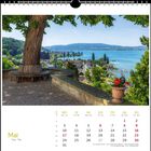 Kalenderseite für Mai. Ein großer Baum mit Bank; darunter herrliche Aussicht auf ein Dorf am See.