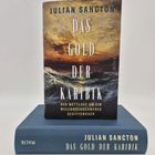 "Julian Sancton: Das Gold der Karibik" Buchcover mit stürmischem Meer; Buch liegt auf blauem Einband.