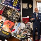 Links sind Bücher mit Titeln wie "THE CASE FOR LOVING", "PASSING". Rechts steht in einem eleganten Raum ein Mann im Anzug.