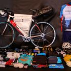 "Europa entdecken mit Guido Lange" und "SCHWARZWALD" auf einem Trikot. Ein Fahrrad mit Zubehör und Kleidung sind zu sehen.