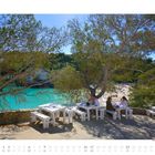 Mai 2027 Kalender. Am Strand sitzen Menschen an weißen Tischen unter Bäumen, mit Blick auf türkisfarbenes Wasser.