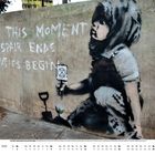 Wandgemälde mit Text: "From this moment despair ends and tactics begin." Kind in Schwarz-Weiß hält Schild mit Symbol.