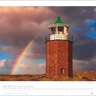 Mai 2027 | Faszination Leuchttürme. Backstein-Leuchtturm mit grünem Dach, daneben ein Regenbogen in dramatischer Wolkenkulisse.