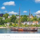 "MAI 2027 | HAMBURG Meine Stadt." Ein Segelschiff auf der Elbe, im Hintergrund grüne Hügel und Häuser.