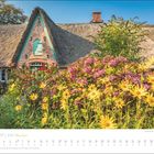 MAI 2027 | SYLT Meine Insel. Historisches Reetdachhaus mit bunten Blumen im Vordergrund, klarer blauer Himmel.