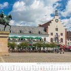 Text: "Luittpold", "Die Pfalz". Pferdestatue auf Steinpodest, dahinter Gebäude mit Glockenturm und Sonnenuhr. Mensen im Freien.