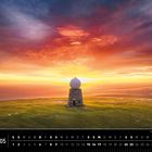 Text: "Norwegen 05". Landschaft mit grünem Hügel, Gebäude mit Kuppel, Meer im Hintergrund und dramatischem Sonnenuntergang.