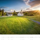 05 und die Zahlen 1 bis 31 stehen unten. Eine Kirche und ein Haus auf einer Wiese im Sonnenuntergang.