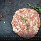 Kalender unten: Mai, Tage nummeriert. Ein rohes Hacksteak auf dunklem Hintergrund, garniert mit Rosmarin und Pfefferkörnern.