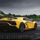 "Lamborghini Revuelto", Kalender für den Monat Mai. Gelbes Sportauto auf einer Rennstrecke, umgeben von Bäumen und bewölktem Himmel.