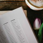 Texte: Oktober, November, Dezember mit Bibelversen. Gegenstände: Cappuccino-Tasse auf Holztisch und eine lila Tulpe.