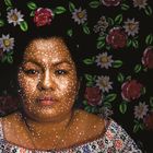 VAEL MARTINEZ, 2021. Portrait einer Frau mit punktuellen Mustern im Gesicht vor einem floralen Hintergrund.
