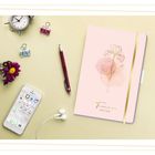 „Timer 2026/2027“ steht auf einem rosa Notizbuch mit goldener Blume. Daneben ein Smartphone, Kopfhörer, Stift und Klammern.