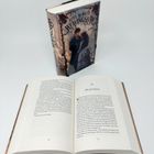 „Der Gefangene“ steht als Kapitelüberschrift im geöffneten Buch. Im Hintergrund ein Roman von Heba Al-Wasity, „Weaving Shaw“.