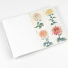 Illustration mit Blumenstempeln und asiatischem Schriftzeichen auf einem aufgeschlagenen, leeren Notizheft links.