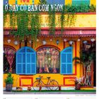 Text: "Ở ĐÂY CÓ BÁN CƠM NGON", "DEZEMBER"
Beschreibung: Gelbes Gebäude mit blauen Fenstern, Pflanzen, Fahrrad.