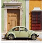 Kalender mit "Dezember 2027", einem grünen VW Käfer vor einer pastellfarbenen Fassade mit Holztür und Fensterläden.