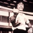 Eine Person mit Anstrengung. Chinesische Schriftzeichen auf dem Hemd. Hintergrund: Gebäude mit Holzstruktur.