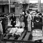 Eine Gruppe Menschen umgibt zwei auf Bahren liegende Personen. Ein Schild zeigt: "Das Rätsel der roten Orchidee".