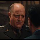 Uniform mit "U.S." Abzeichen; ein Mann in Uniform spricht ernst mit einer anderen Person im Raum.