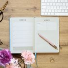 Im Bild sind die Texte "FEBRUAR" und "NOTIZEN" zu sehen. Ein offener Planer mit einem rosa Stift liegt auf einem Schreibtisch.