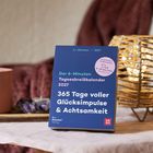 Der 6-Minuten Tagesabreisskalender 2027 verspricht 365 Tage voller Glücksimpulse & Achtsamkeit. Auf einem Tisch dekoriert.