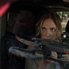 Eine Frau mit entschlossener Miene zielt mit einer Armbrust aus einem Auto. Ein Mann sitzt konzentriert neben ihr im Auto.