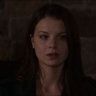 Keine Texte vorhanden. Eine Frau mit langen braunen Haaren blickt ernst. Hintergrund ist eine Steinwand.