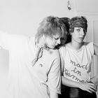 Die Frau rechts trägt ein Shirt mit "mad in Germany". Sie trägt ein Stirnband und hat eine Hand in die Hüfte gestützt.