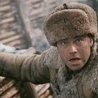 Ein Mann in Winterkleidung, im Graben, hält einen Hammer. Sein Gesicht wirkt entschlossen und konzentriert.