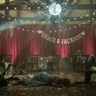 Text "Grace & Jackson" vor rotem Vorhang. Frau liegt am Boden in einem leeren, dekorierten Saal mit Disco-Kugel.