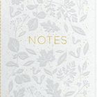 Schriftzug "NOTES" in der Mitte, umgeben von zarten, geprägten Blättern und Zweigen auf hellem Hintergrund.